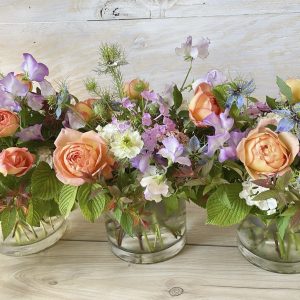 Peach roses, lavender sweet peas and spring flowers in glass vases